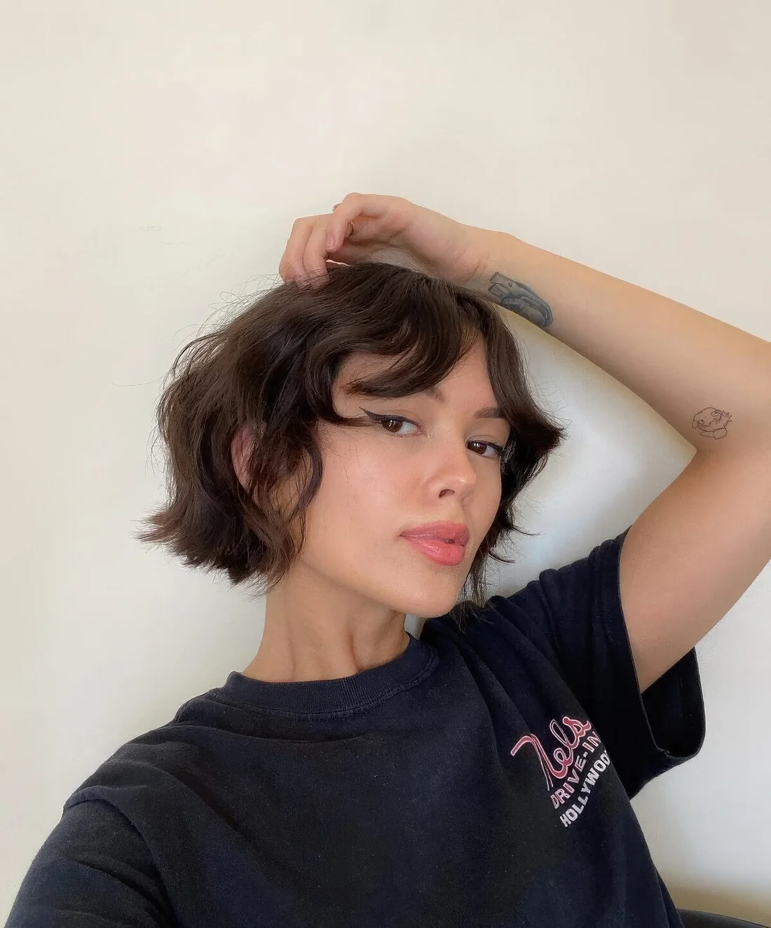 Brown bob with waves and a messy texture plus wavy curtain bangs are.
