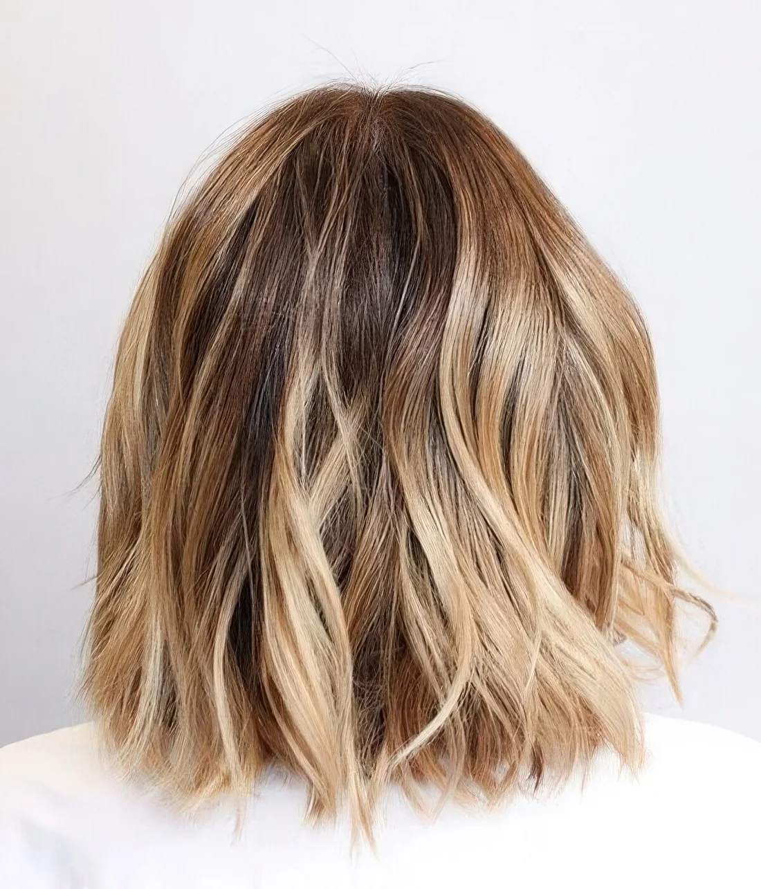 Bit messy long bronde bob with golden and bleached blonde balayage and a darker root.