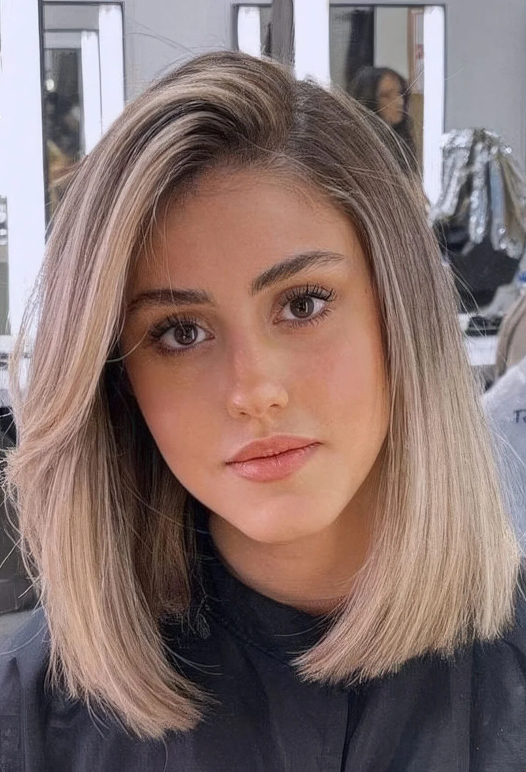 Blonde long bob with a darker root and curved ends.