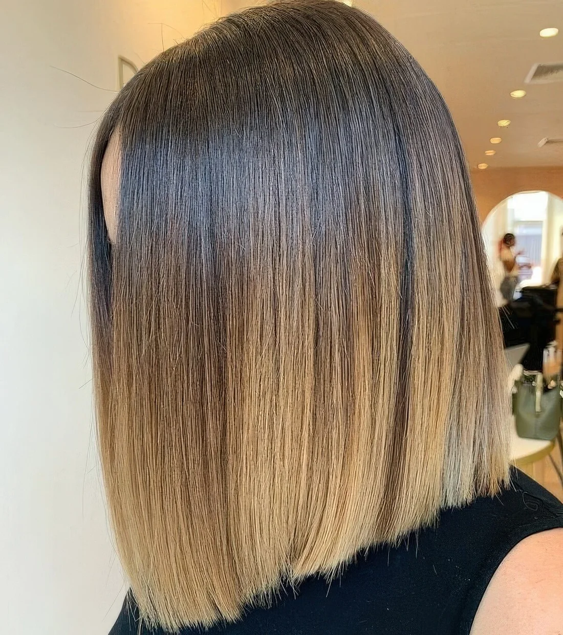 Cold brunette long bob with an ombre effect with a blonde shade and center part.