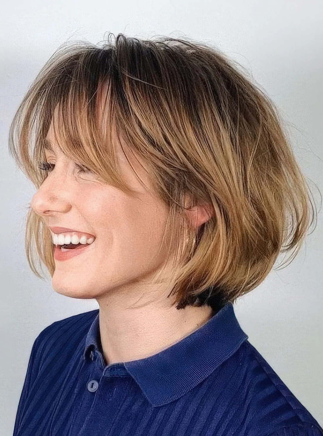 Chin-length bob with honey blonde balayage and long curtain bangs, curved ends and a bit of volume.