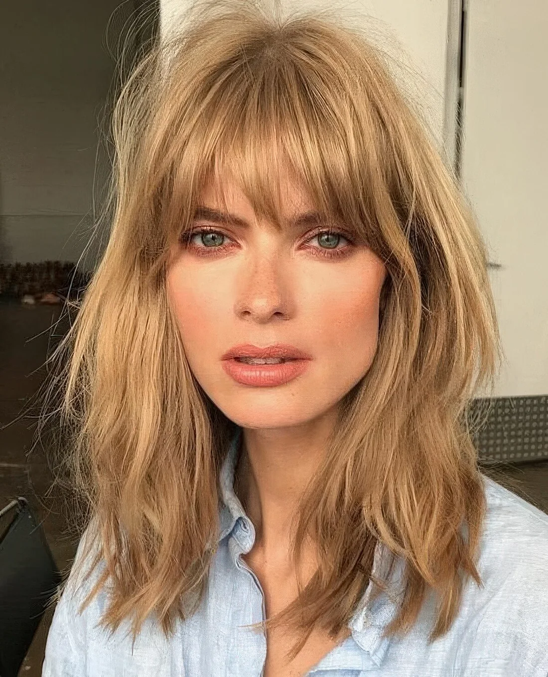 Layered honey bronde long bob with shaggy locks and with overgrown and very natural bangs.