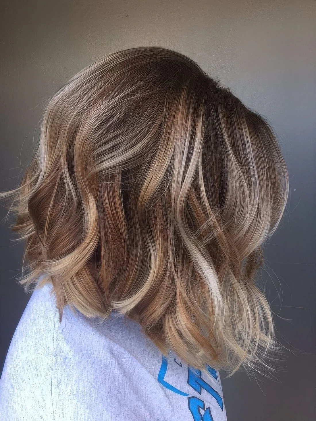 Long bronde bob with waves and blonde highlights, with a lot of volume.