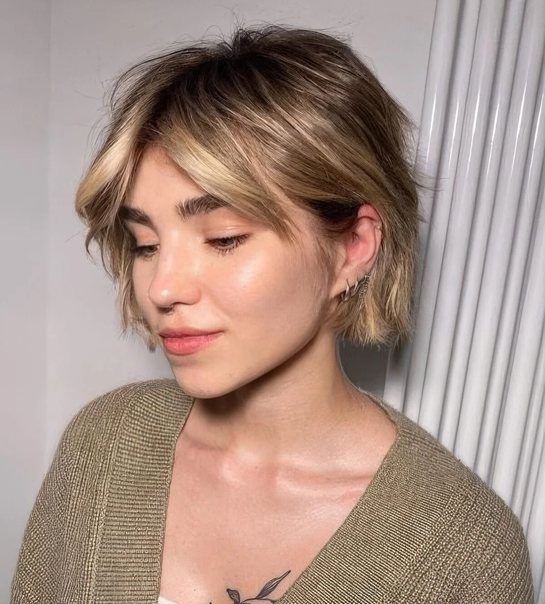 Messy and shaggy jaw-length bob with blonde balayage and short curtain bangs plus waves.