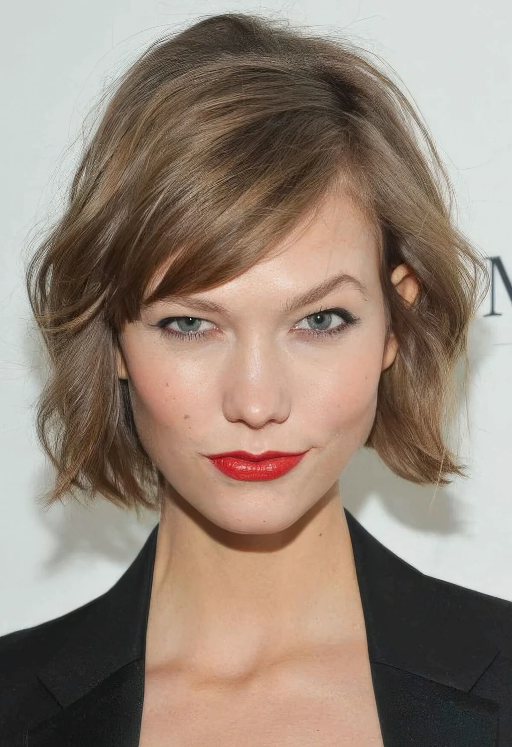 Mousy brown jaw-length bob with side bangs and messy waves.