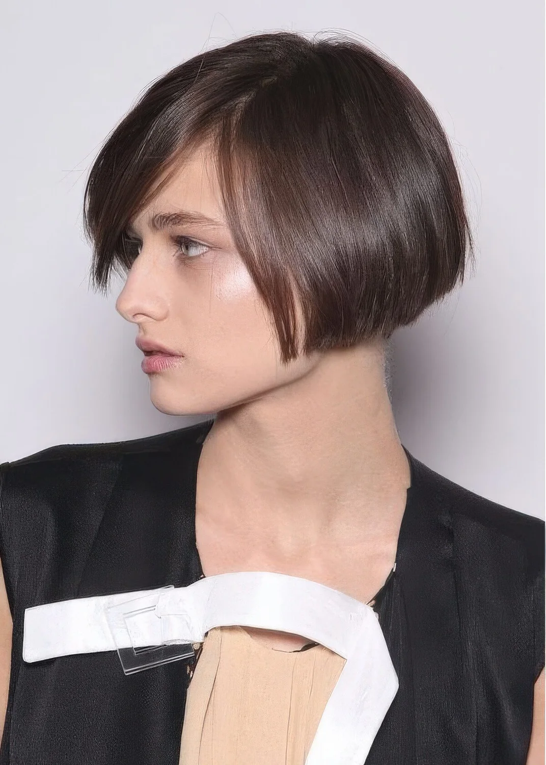 Brunette ear-length bob with side part, with a sleek finish.