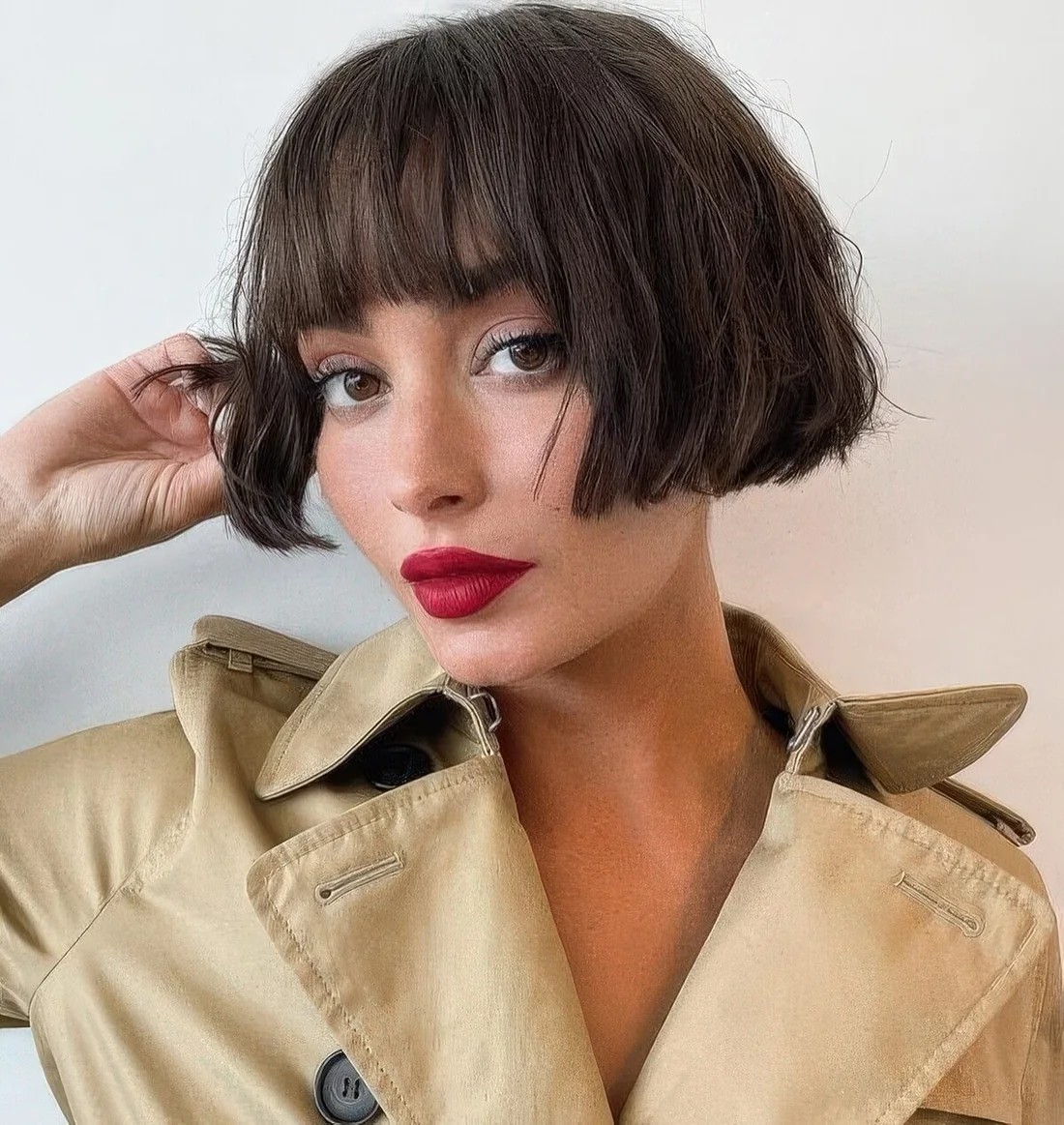 Chic dark brunette ear-length bob with a classic fringe and messy waves.