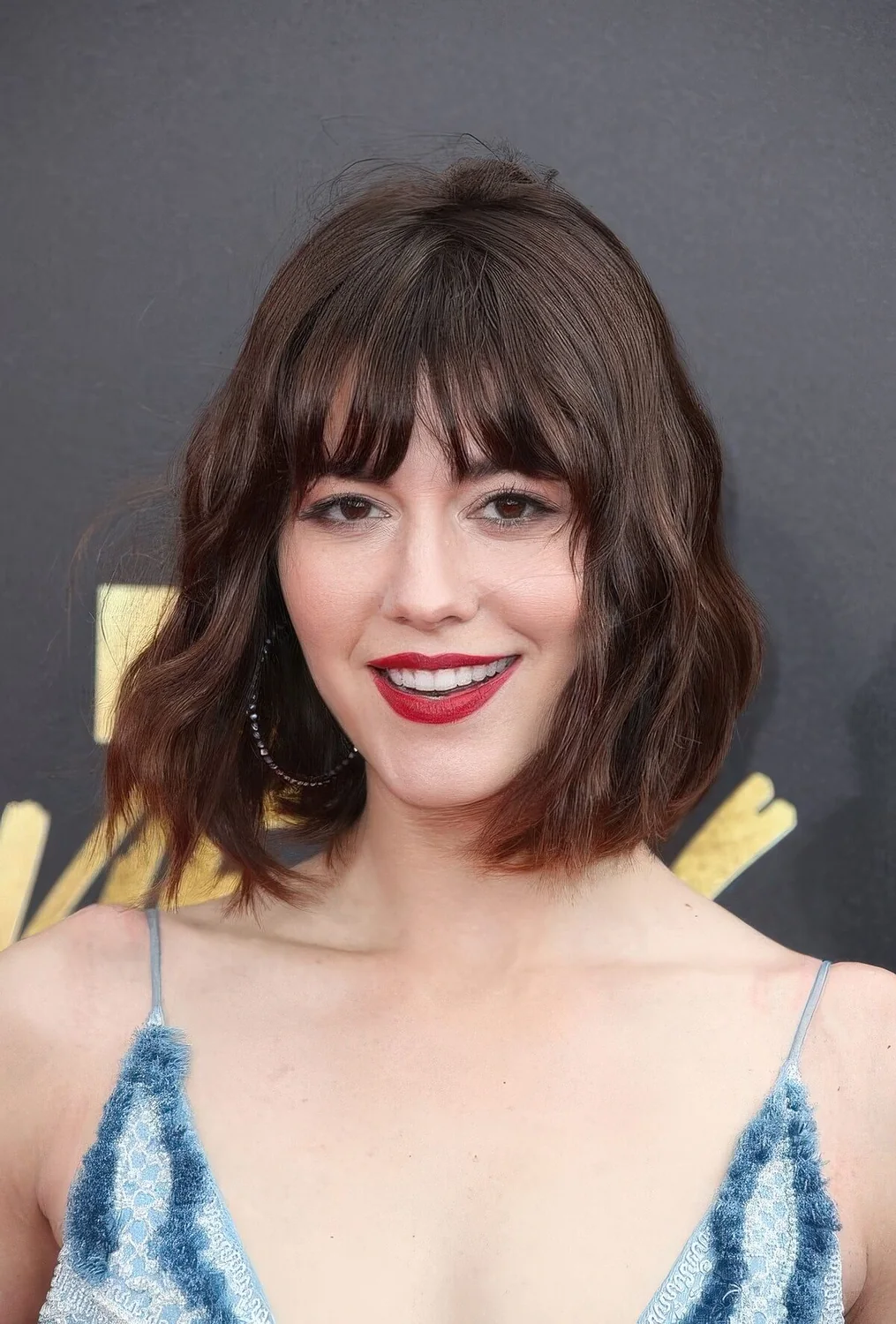 Dark brunette long bob with wispy bangs and waves.