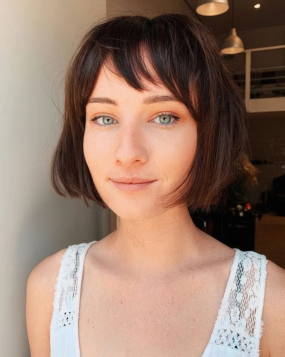 Dark brunette chin-length bob with wispy bangs.