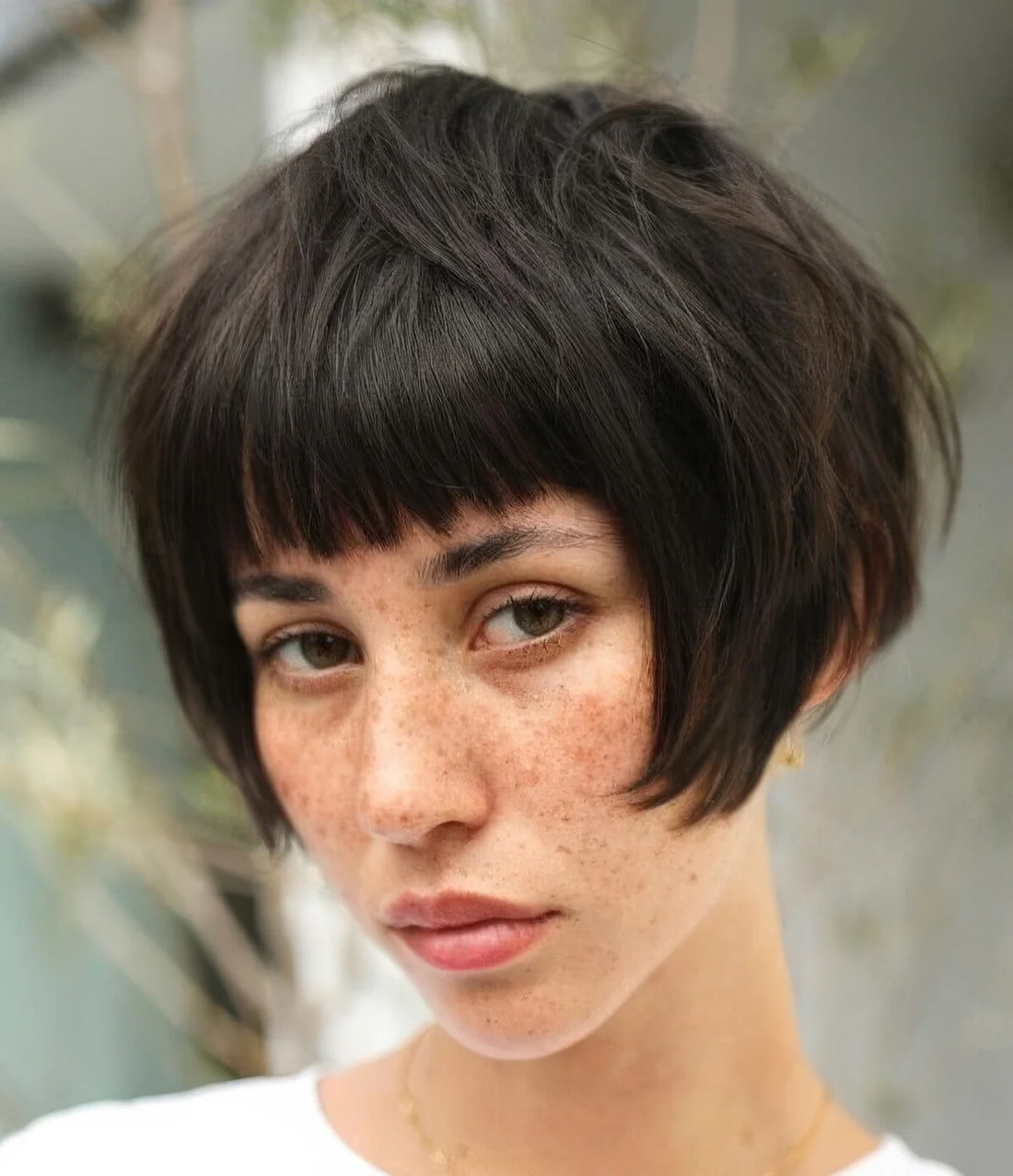 Dark brunette ear-length bob with a classic fringe and a messy volume.