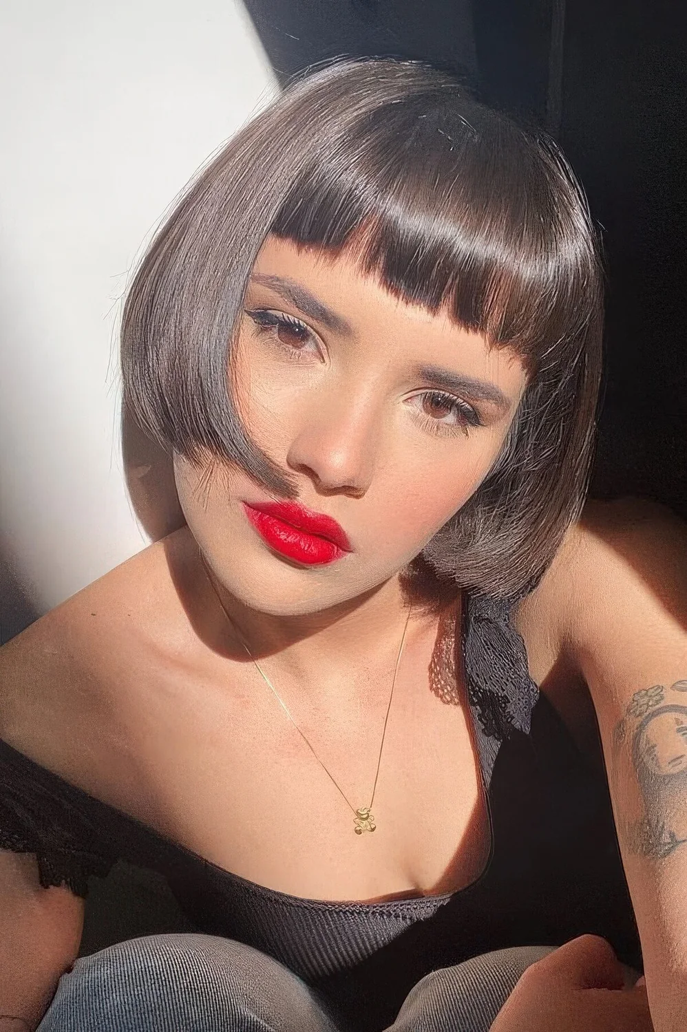 Dark brunette ear-length bob with baby bangs and curled ends plus a shiny finish.