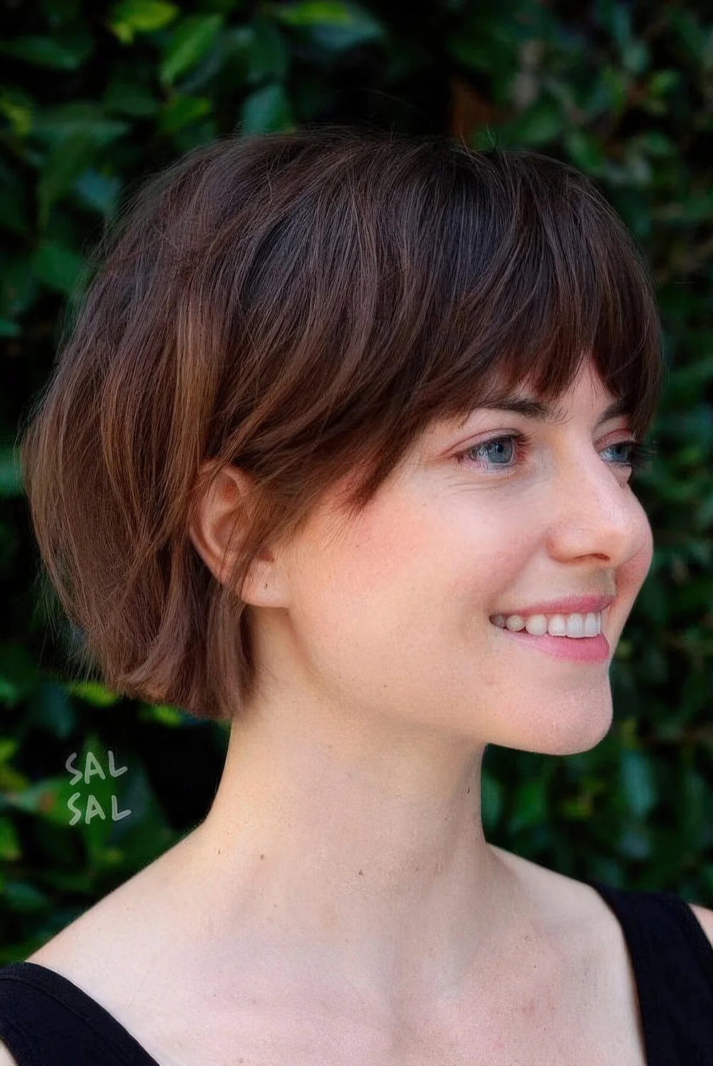 Dark brunette jaw-length bob with caramel balayage and layered bangs.