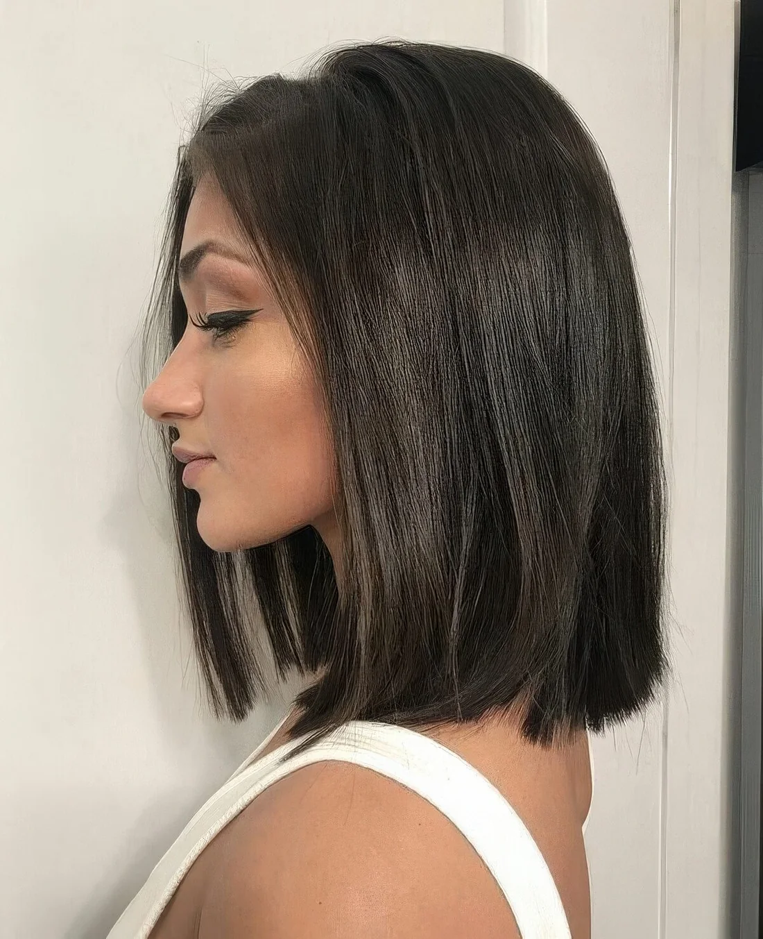 Dark brunette shoulder-length blunt bob.