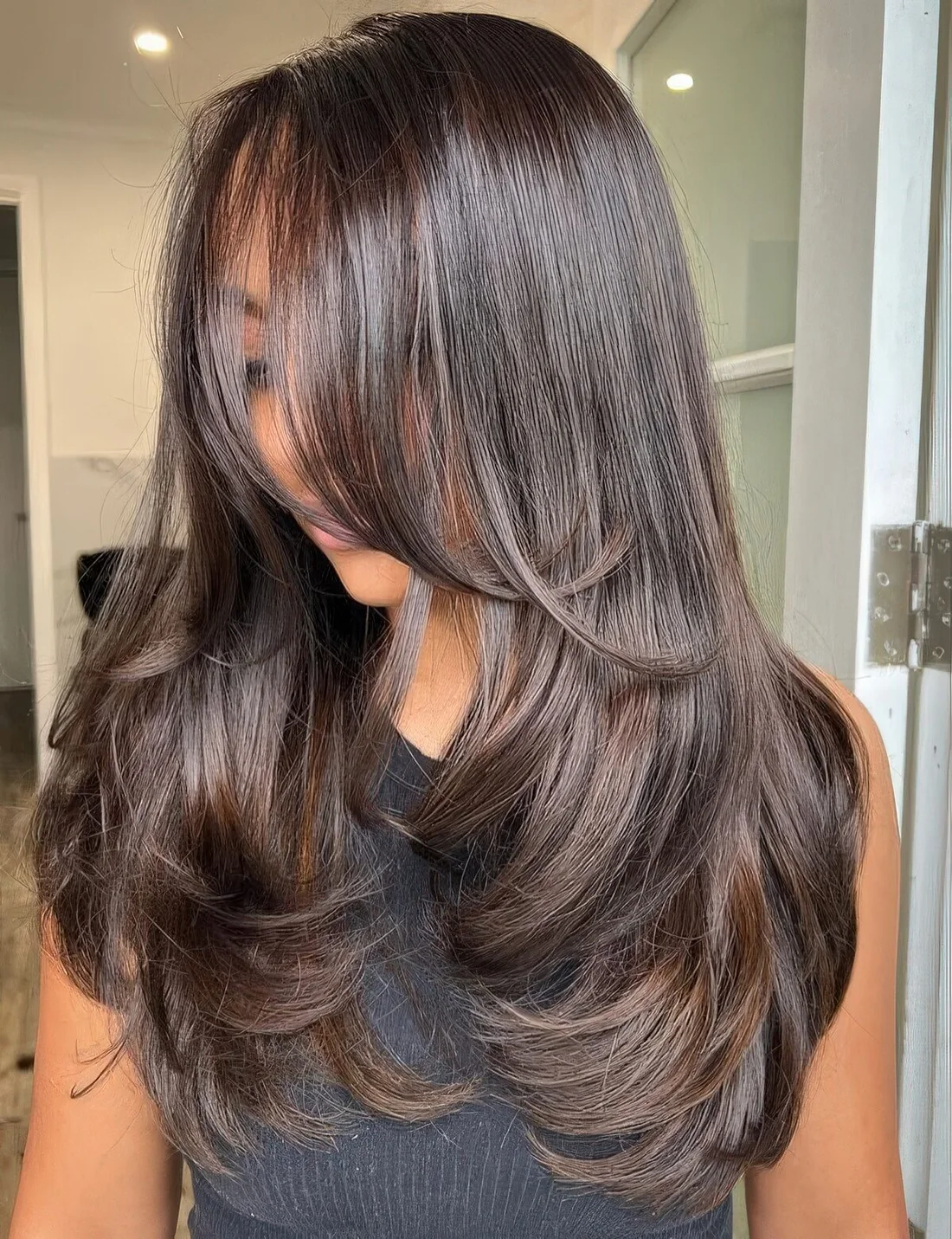 Dark brunette butterfly haircut with a shiny finish and wavy ends.