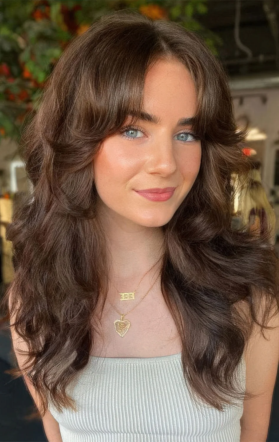 Brunette butterfly haircut with curtain bangs and waves.