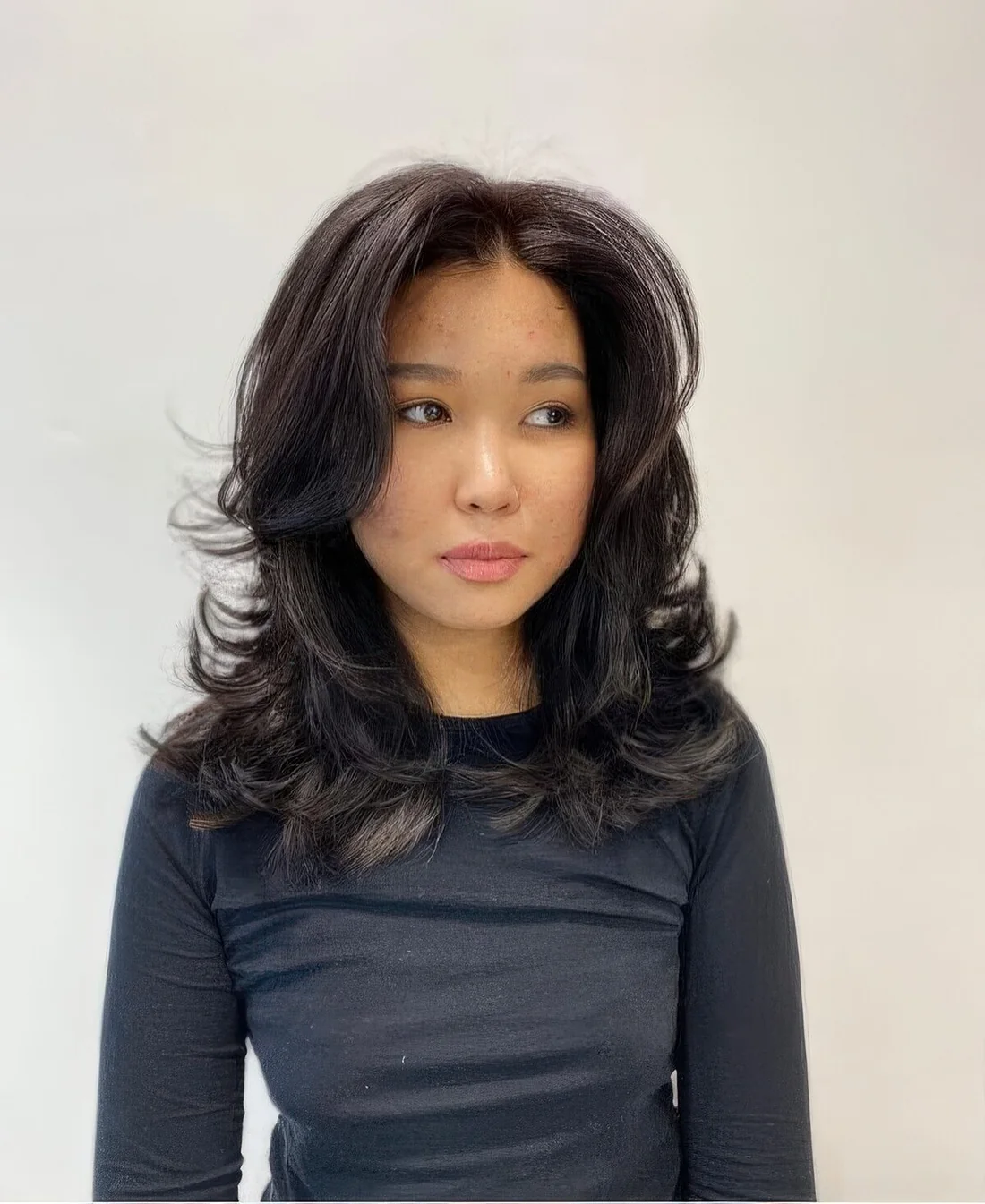 Black medium butterfly haircut with a lot of volume and curved ends.
