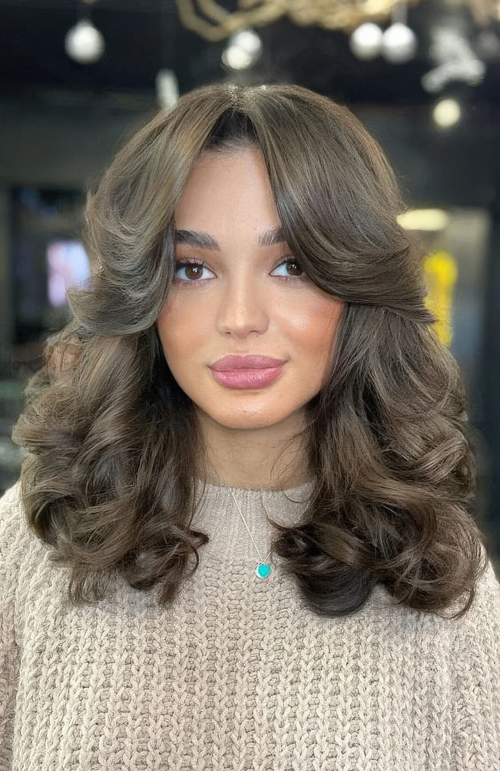 Brunette medium butterfly haircut with side bangs and curls.