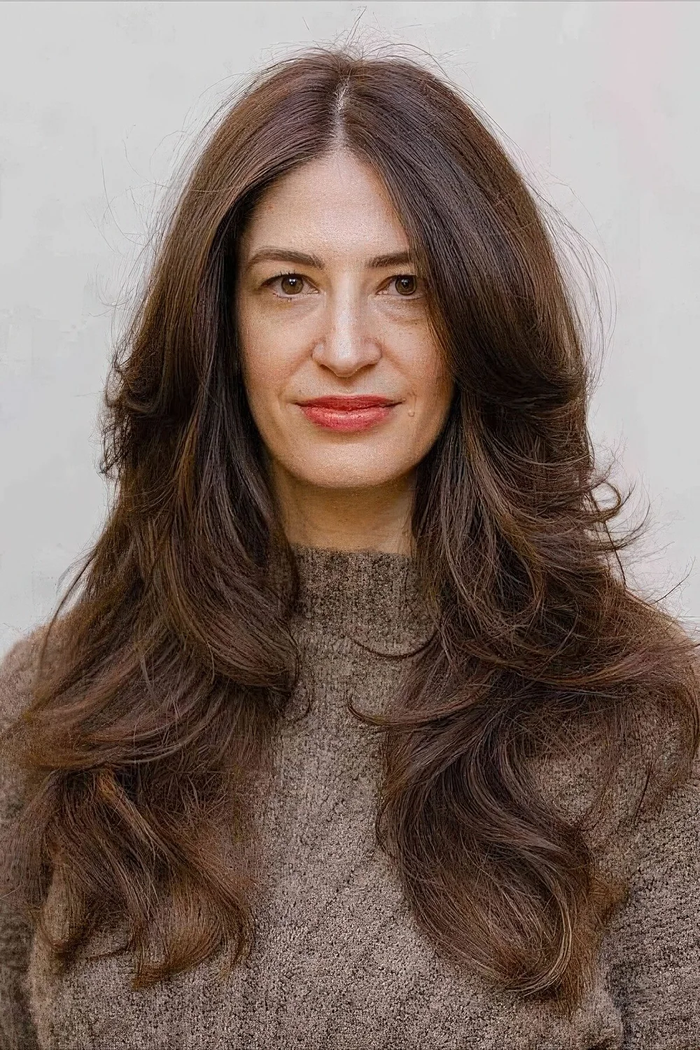 Dark brunette butterfly haircut with long curtain bangs and waves.
