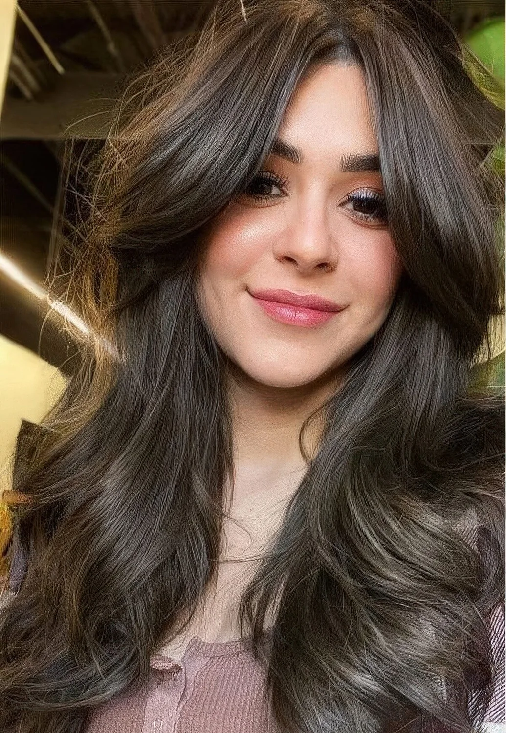 Long brunette butterfly hairstyle with bottleneck bangs and waves plus a lot of volume.