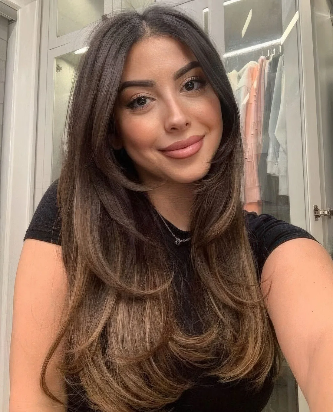 Long dark brunette butterfly haircut with long curtain bangs and curled ends plus caramel balayage.