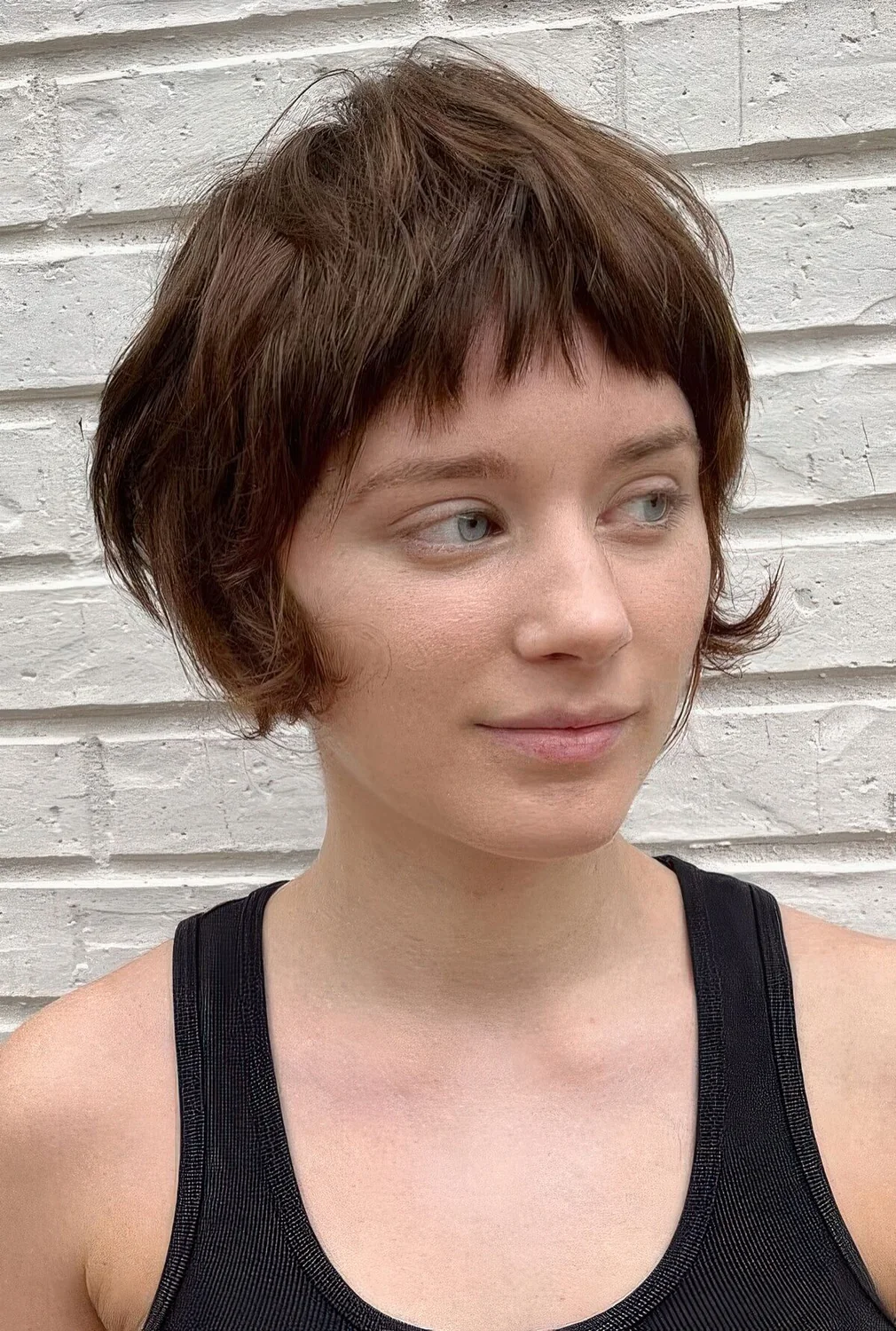 Brown bixie with a layers and textured touches, a short fringe and curved ends on the sides.