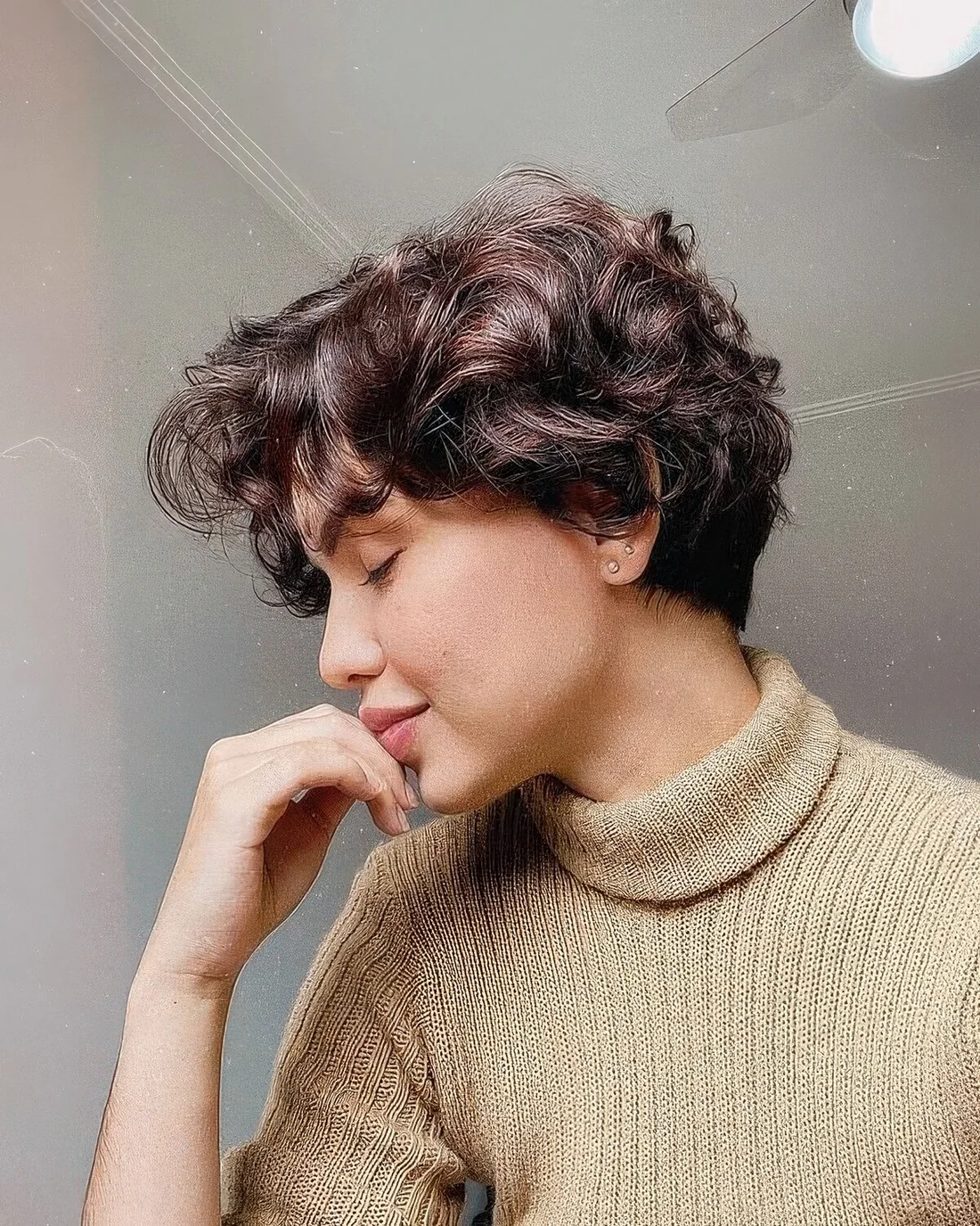 Dark brown wavy and curly pixie with a bit of short bangs.