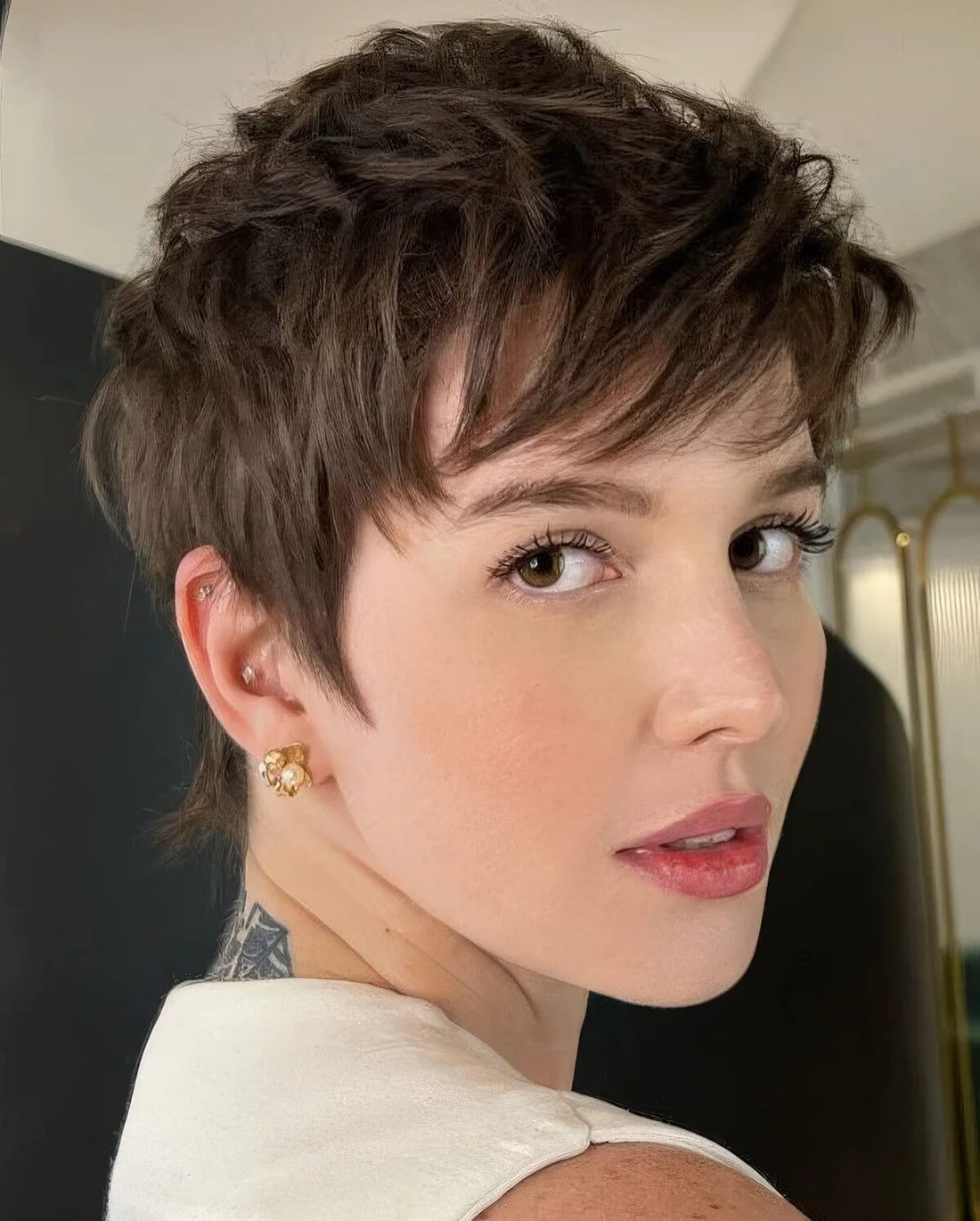 Layered brunette pixie with feathered layers that provide movement and longer sides.