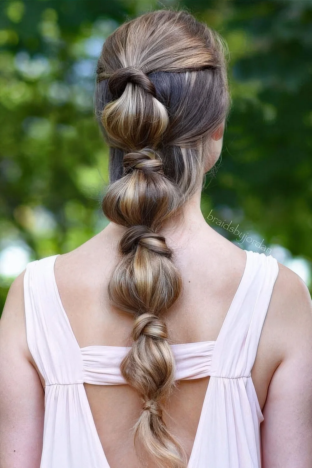 Bubble braid with a volumetric top and some hair accenting the ponytail.