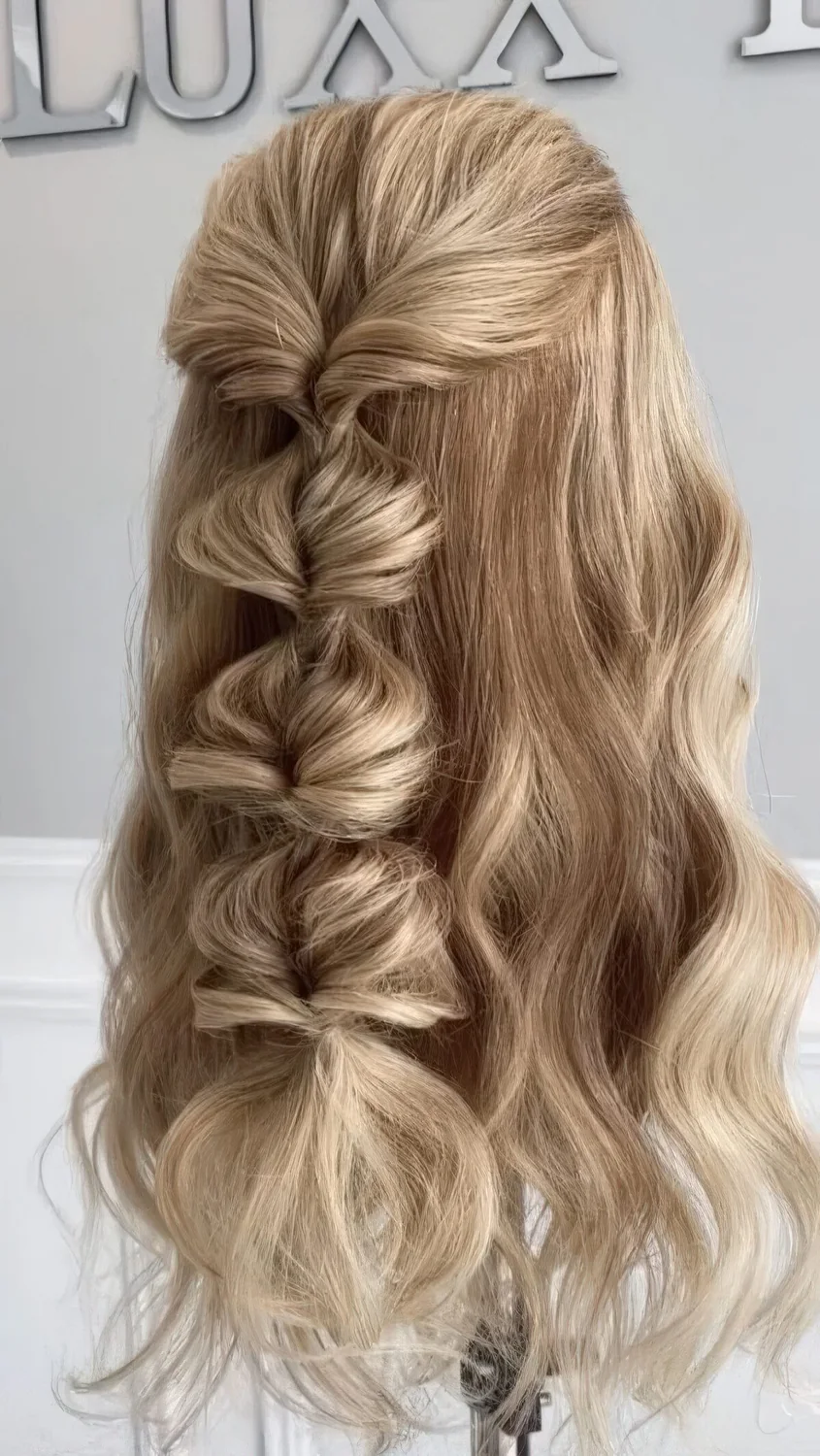 Half updo with a volumetric top and waves down, a loose bubble braid as an accent.