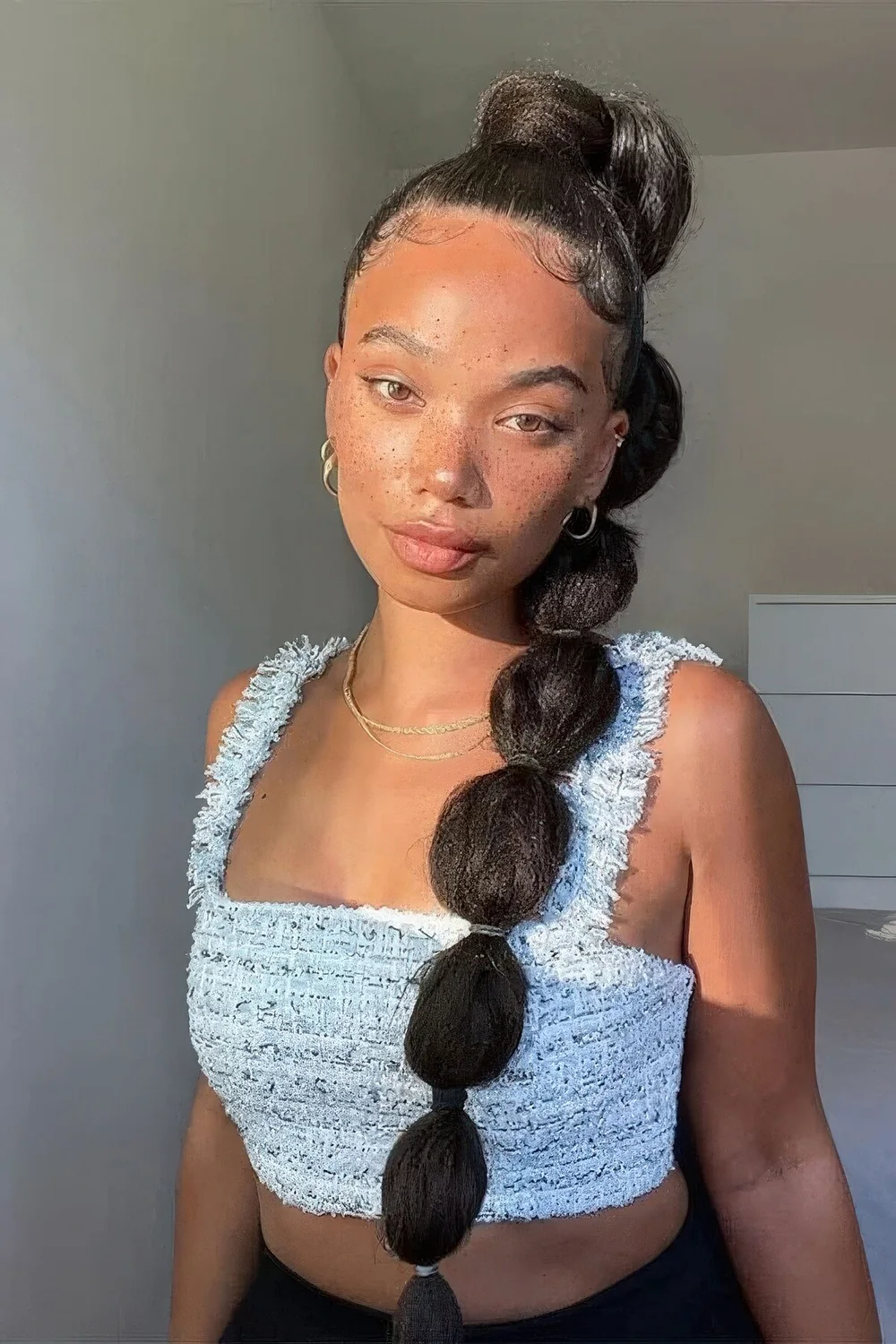 Textured high bubble ponytail worn over one shoulder.