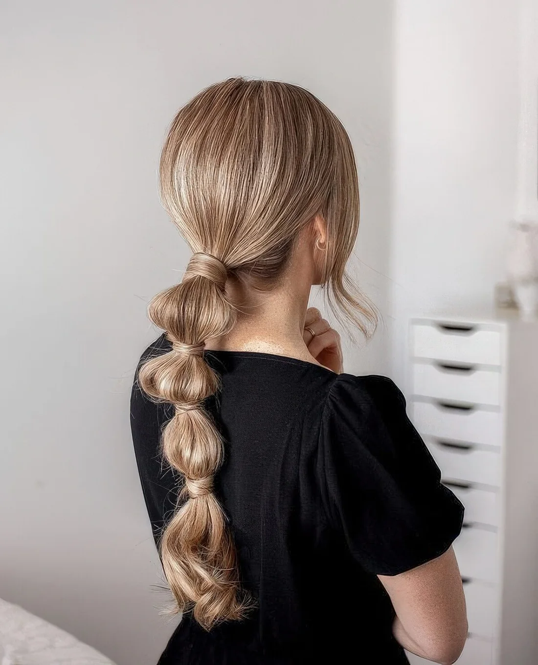 Modern bubble ponytail with a sleek volumetric top and some face-framing hair.