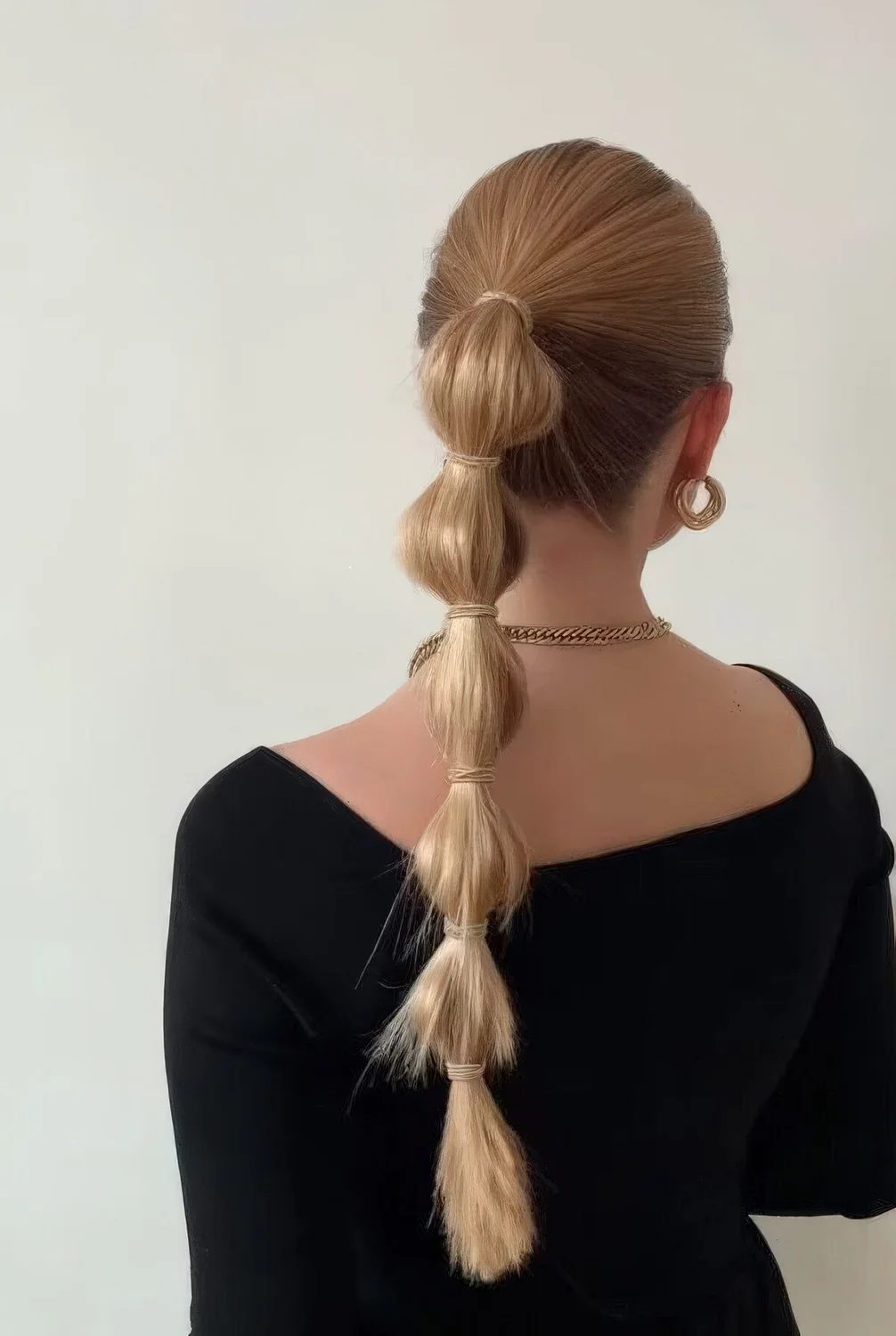 Modern midi bubble ponytail with a sleek top and some hair elastics.