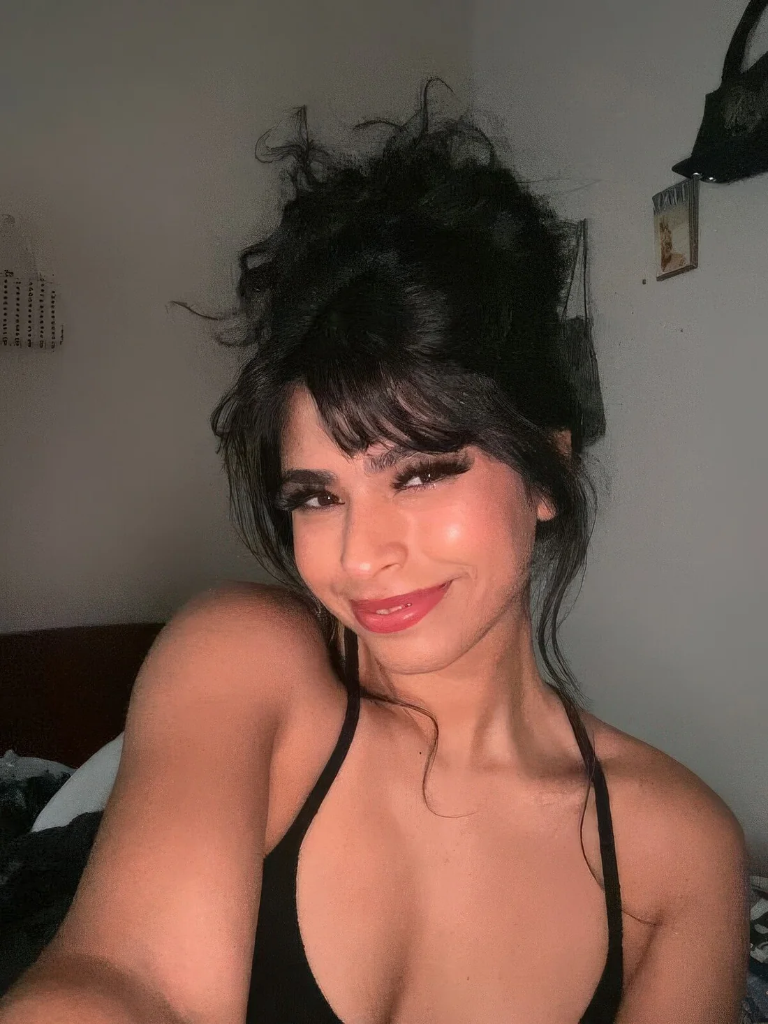 Photo showing curly top knot with layered bangs, with the hairstyle clearly visible.