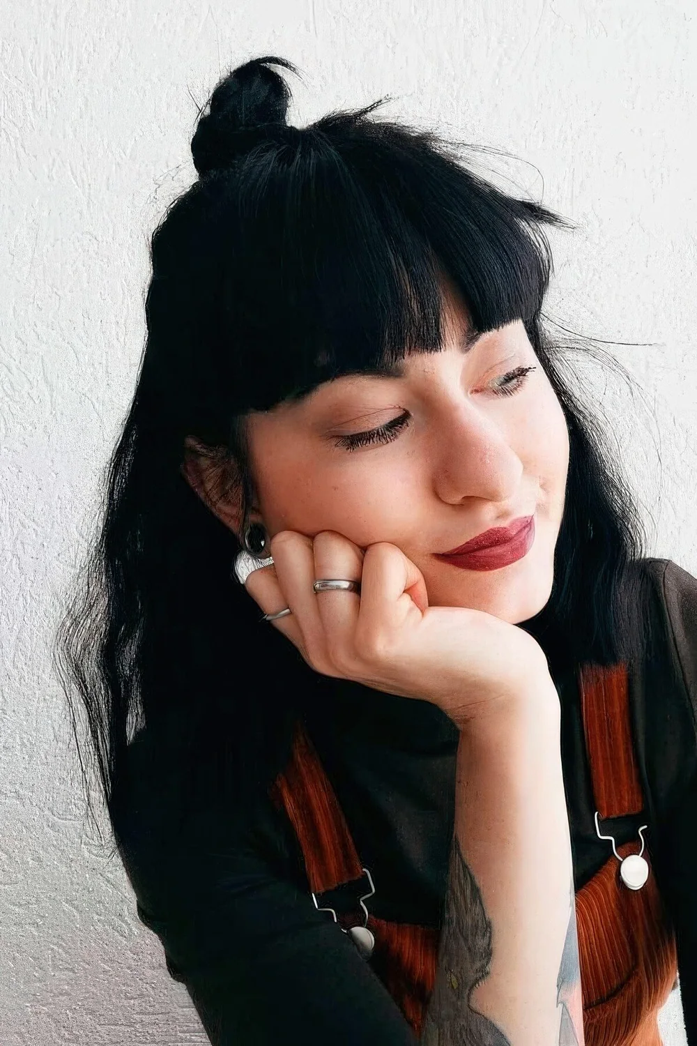 Half updo with a small top knot and bottleneck bangs.