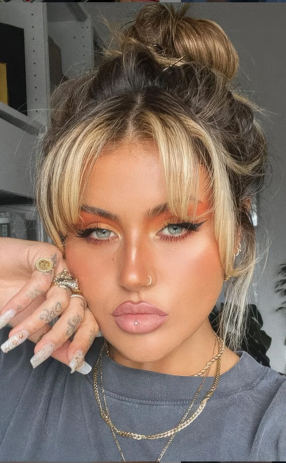 Messy top knot with short curtain bangs.