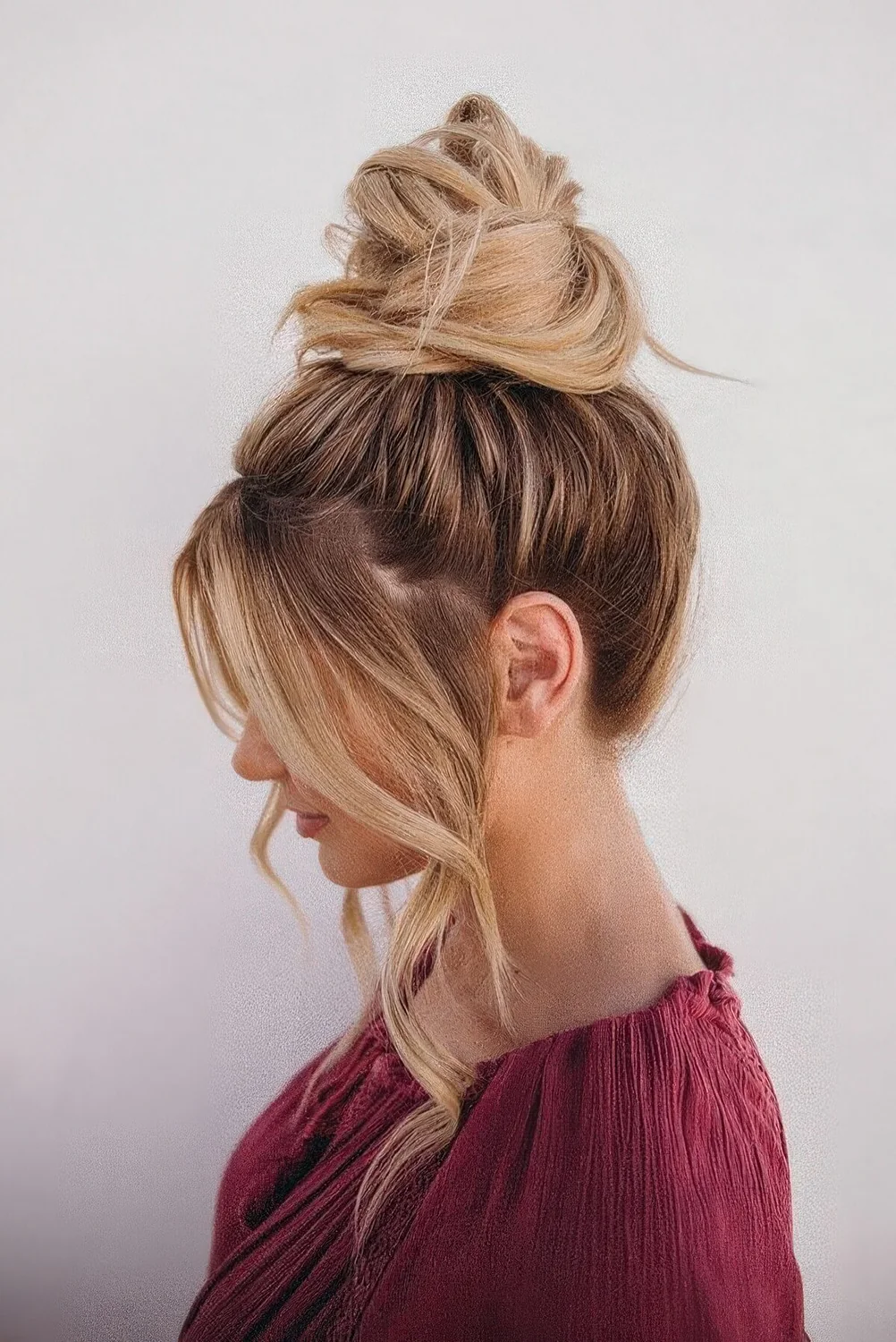 Messy wrapped top knot with long curtain bangs.