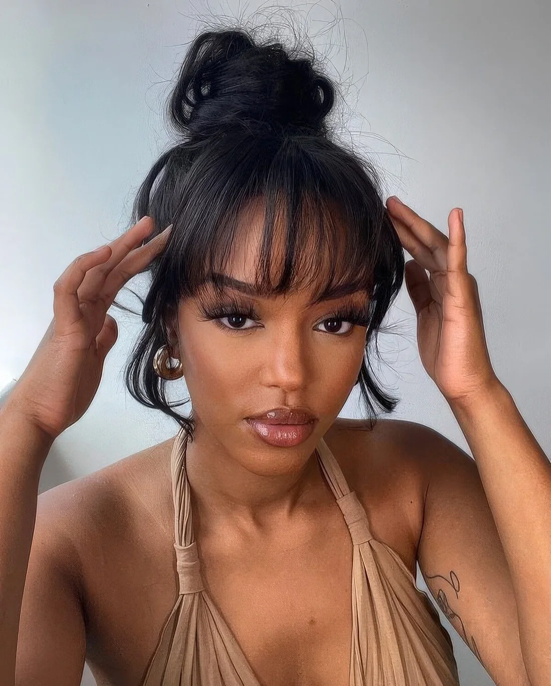 Messy wrapped top knot with wispy bangs.