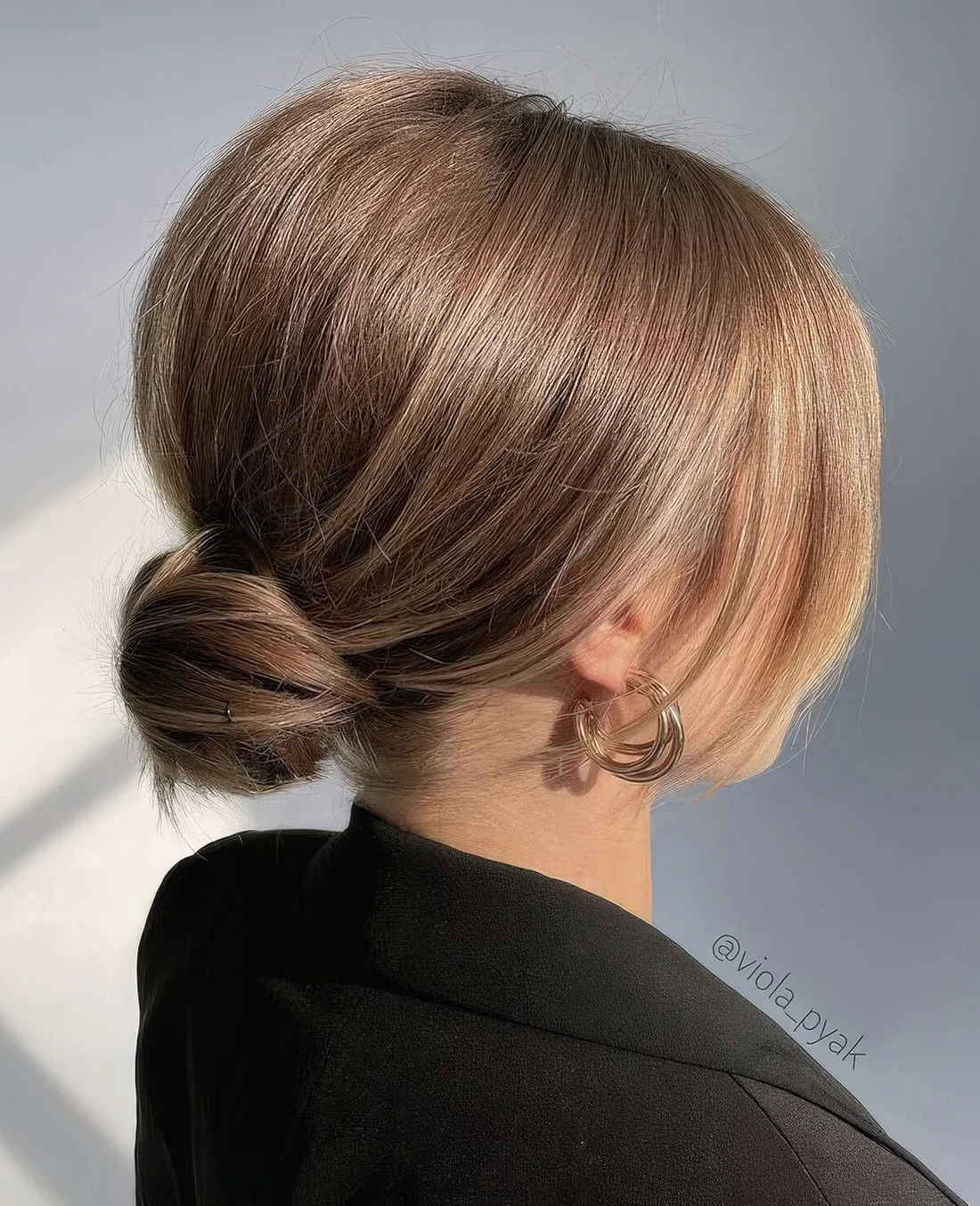 Photo showing sleek low bun with curtain bangs, with the hairstyle clearly visible.