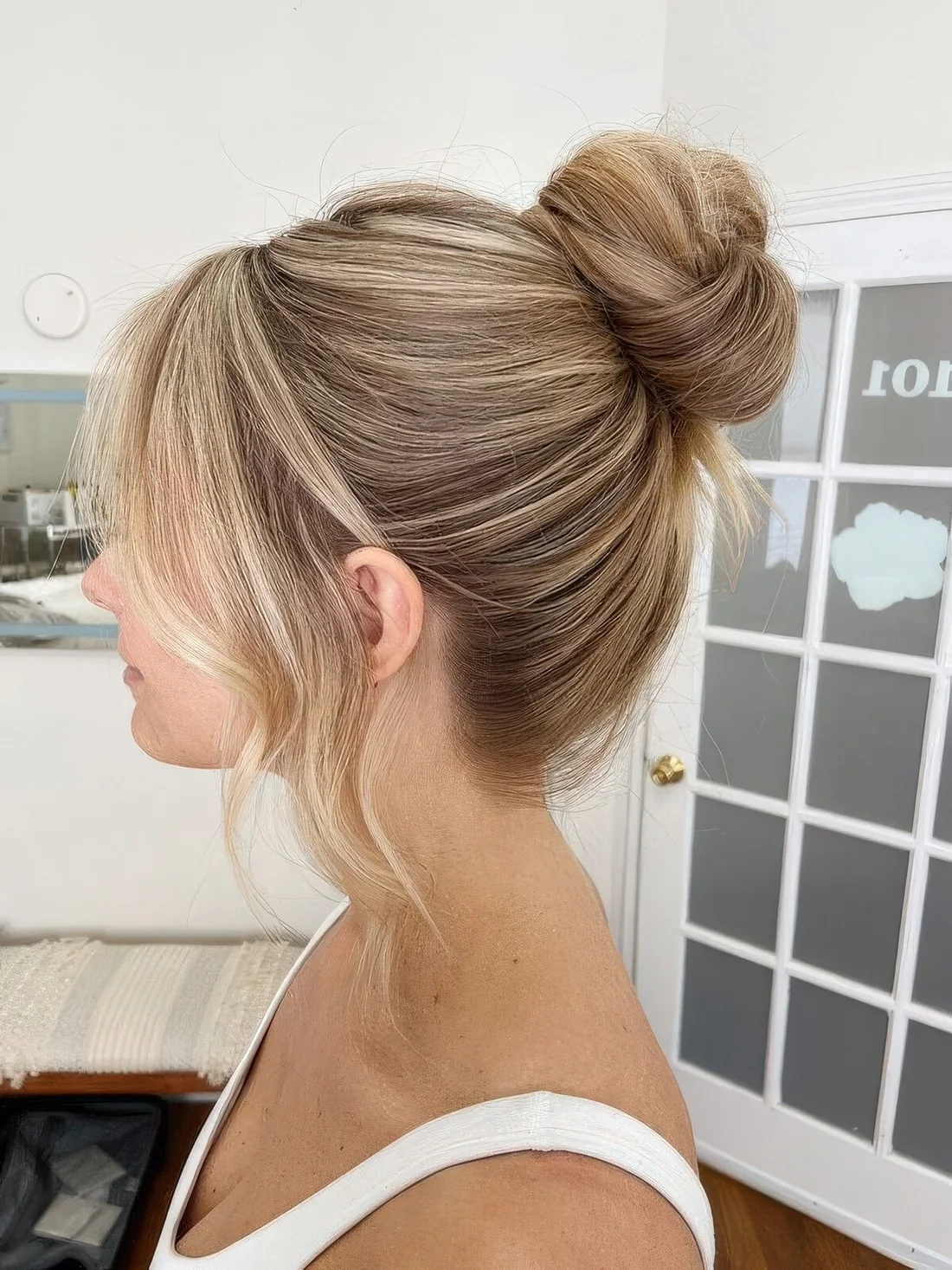 Sleek top knot with wavy curtain bangs.