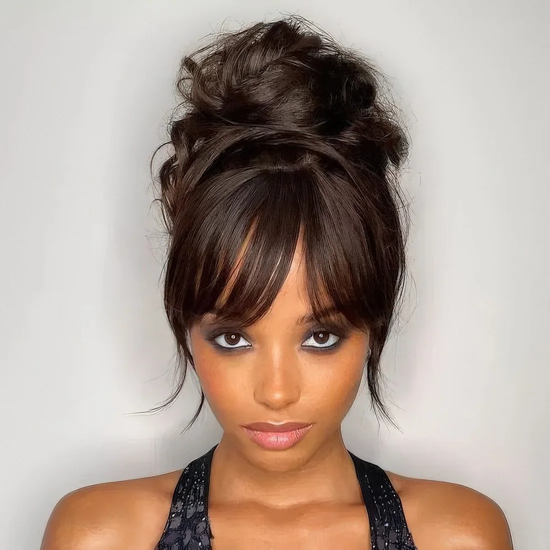 Volumetric messy top knot with bottleneck bangs.