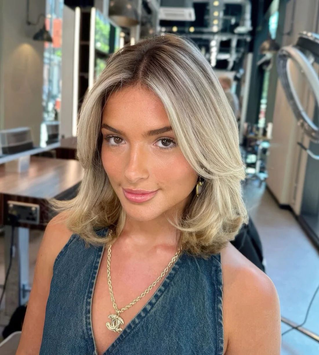 Shoulder-length butterfly bob with cold blonde balayage, curled ends and some volume.