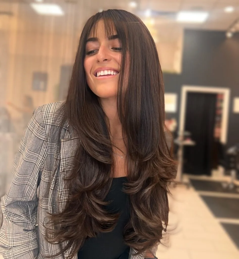 chest wavy brunette layers with curtain fringe shown as a butterfly haircut long hairs idea, featuring center part