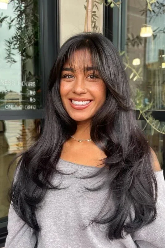 chest wavy black layers with curtain fringe shown as a butterfly haircut long hairs idea, featuring wavy texture