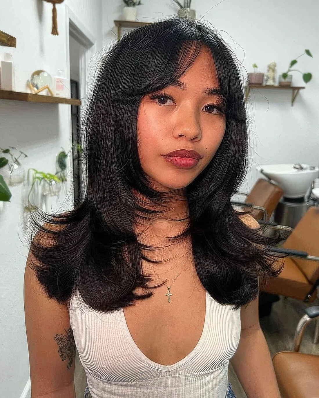 Black butterfly haircut with curtain bangs and curled ends.