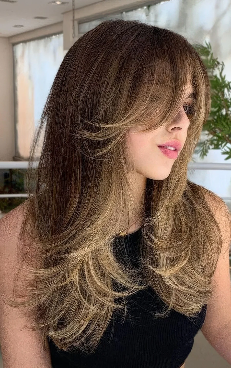 Brunette butterfly haircut with blonde highlights and a curtain fringe that.