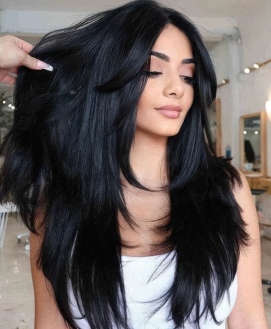 Long black butterfly haircut with curtain bangs and curled ends.