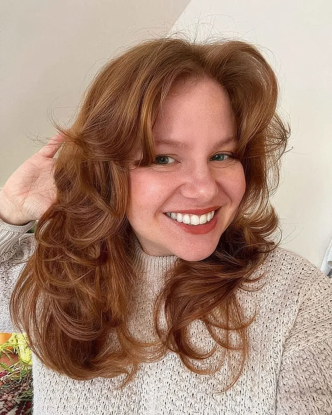 Ginger butterfly haircut with curtain bangs and curled ends plus volume.