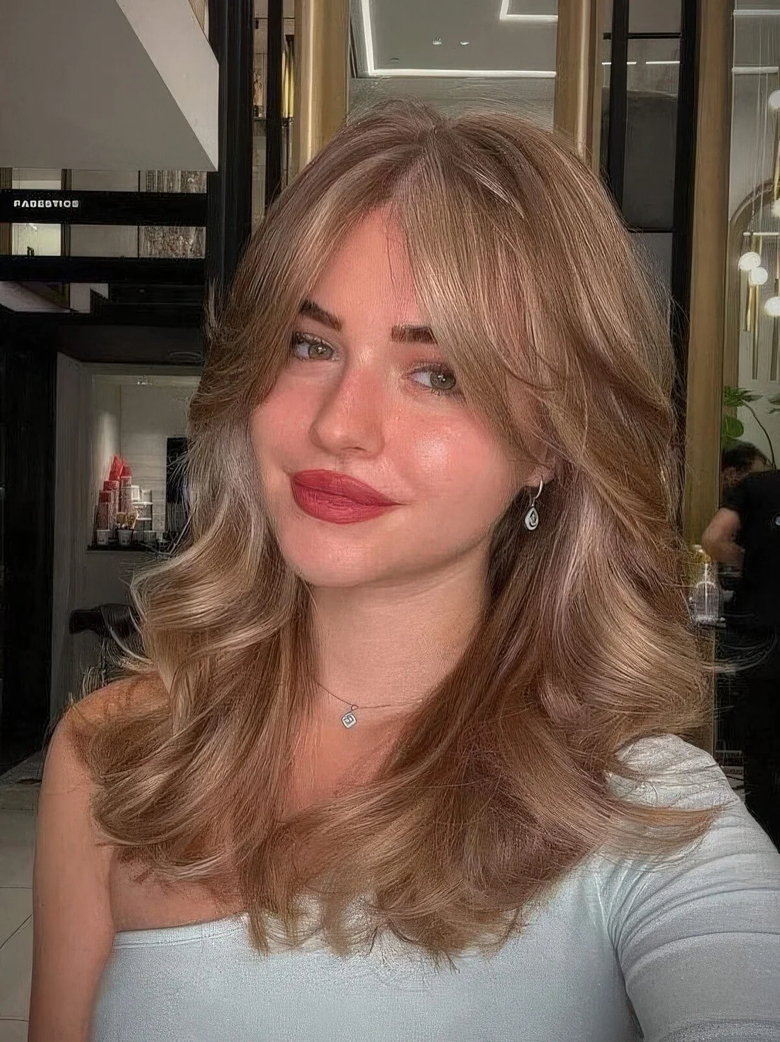 Bronde wavy hairstyle done on a butterfly haircut, with curtain bangs.