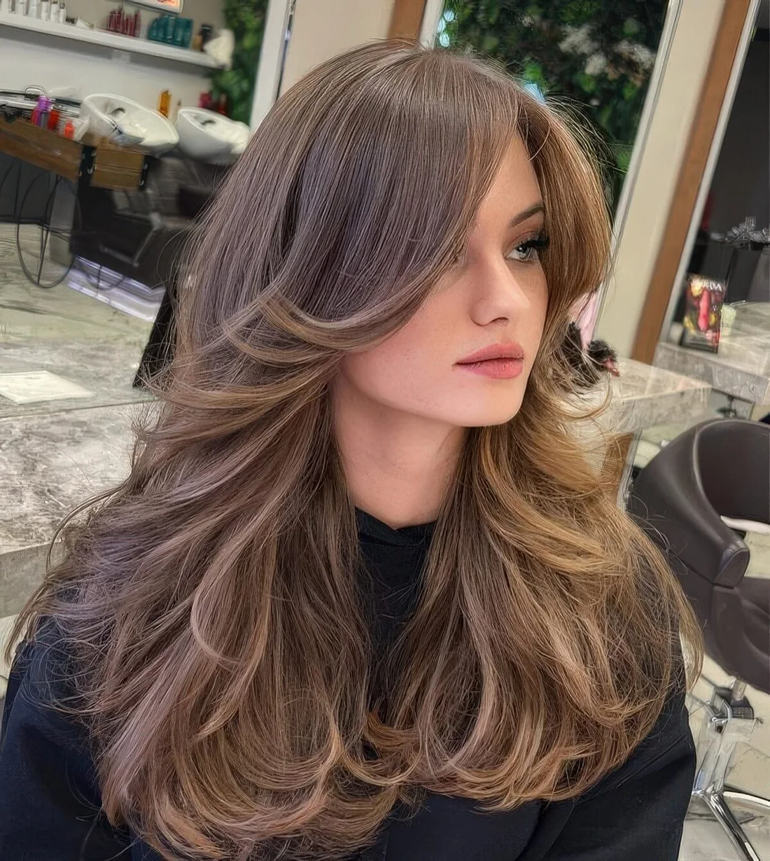 Long butterfly haircut with long curtain bangs and curled ends.