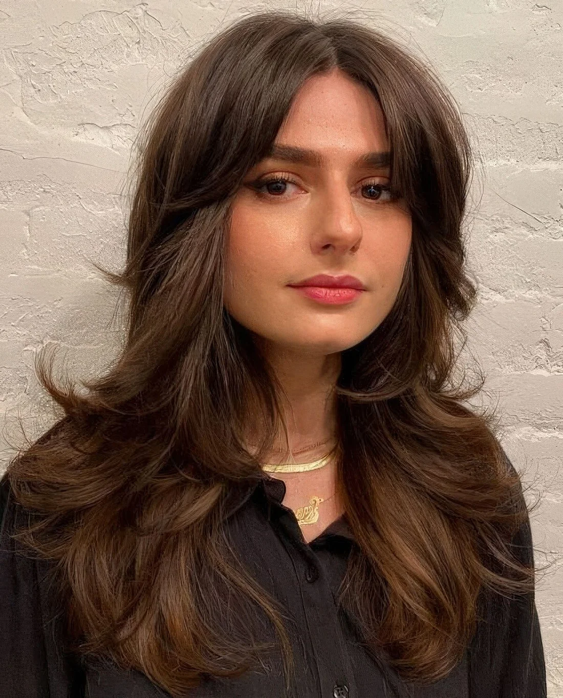 Long brown butterfly haircut with curled ends and short curtain bangs.